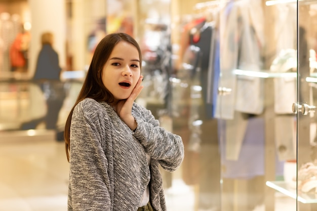 Compras Una joven en un centro comercial está sorprendida por los precios.