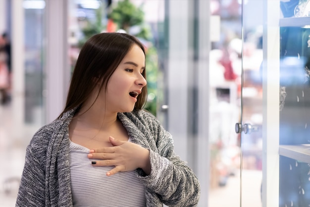 Compras Una joven en un centro comercial está sorprendida por los precios.