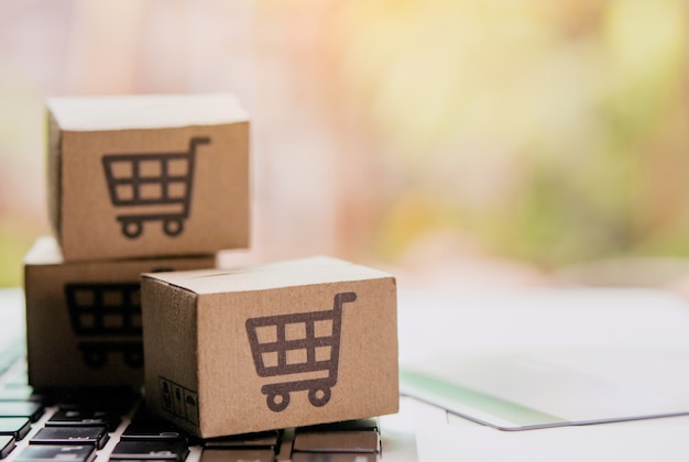 Compras en línea: cajas de papel o paquetes con el logotipo de un carrito de compras y una tarjeta de crédito en el teclado de una computadora portátil. Servicio de compra en la web online y ofrece entrega a domicilio.