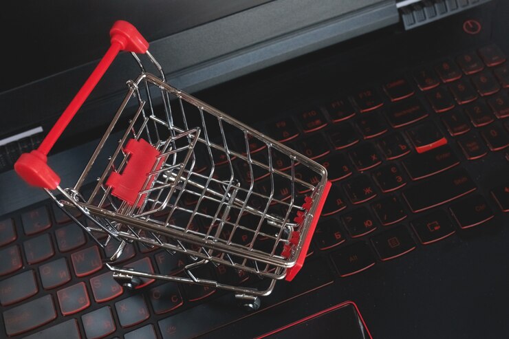 Foto compras en línea carrito de compras en el teclado negro. carretilla metálica roja en un teclado portátil. servicio de compras en la web en línea. ofrece servicio a domicilio. copyspace para texto.