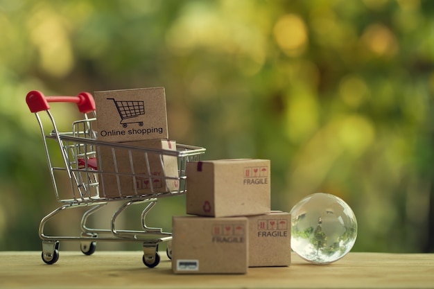 Compras en línea y concepto de comercio electrónico: cajas de papel en carrito de compras y globo de cristal.