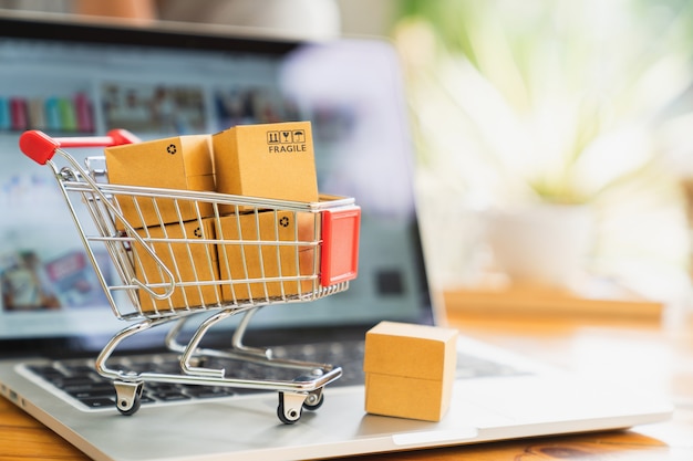 Foto compras en línea y concepto de entrega, cajas de paquete de producto en carro y laptop