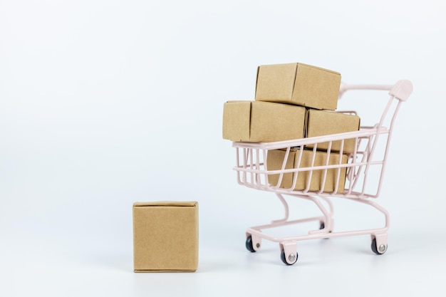 Foto compras en línea y concepto logístico caja de papel en pequeño carrito de compras fondo blanco servicio de entrega a domicilio de supermercado importación exportación finanzas comercio