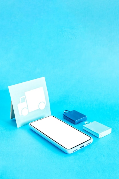 Compras en línea y envío Concepto de entrega Teléfono inteligente y formas de papel sobre fondo azul