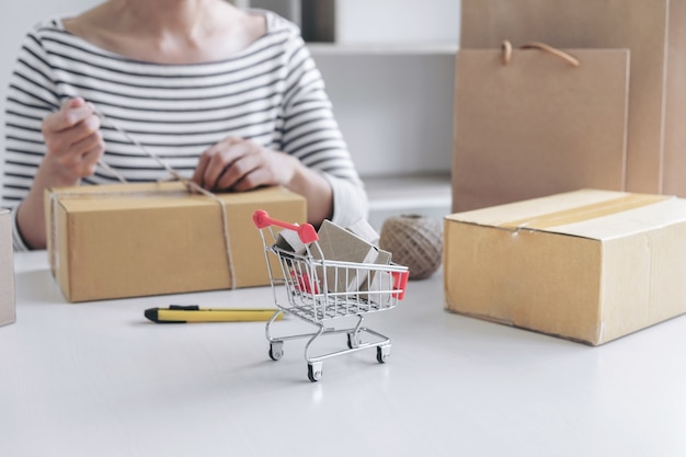 Compras en línea de Internet, mujer joven del vendedor que prepara el paquete que se enviará Mail transportat