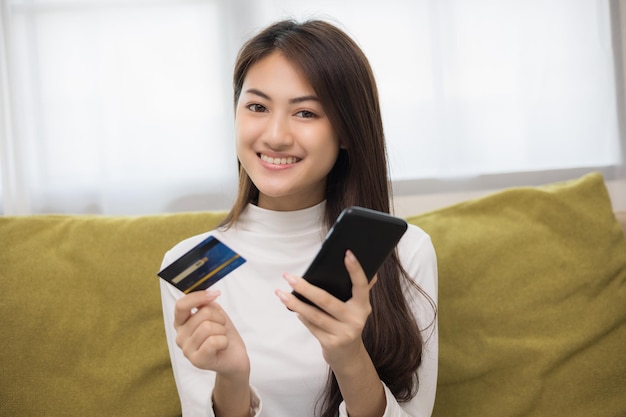 Compras en línea Joven adolescente asiática ingresa el número de serie de la tarjeta de crédito en el teléfono inteligente para el pago de compras Comprar artículo en línea entrega en casa Mujer sonriente que se siente feliz