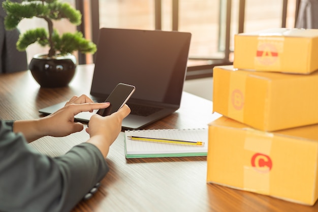 Las compras en línea jóvenes comienzan pequeñas empresas en una caja de cartón en el trabajo.