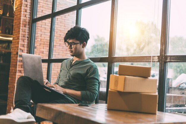 Las compras en línea jóvenes comienzan pequeñas empresas en una caja de cartón en el trabajo.