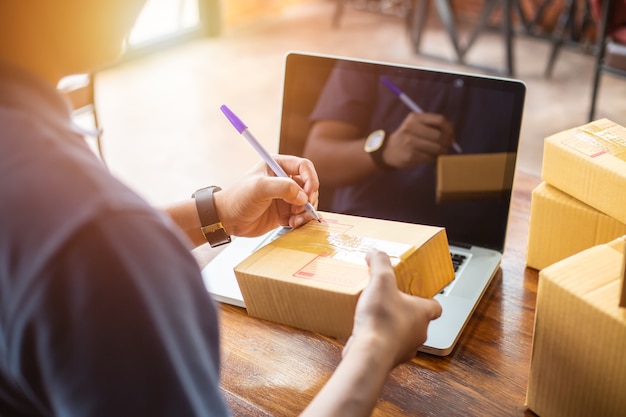 Las compras en línea jóvenes comienzan pequeñas empresas en una caja de cartón en el trabajo.