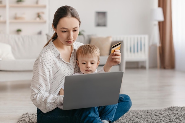 Compras en línea madre joven e hijo pequeño que piden productos con computadora portátil y tarjeta de crédito