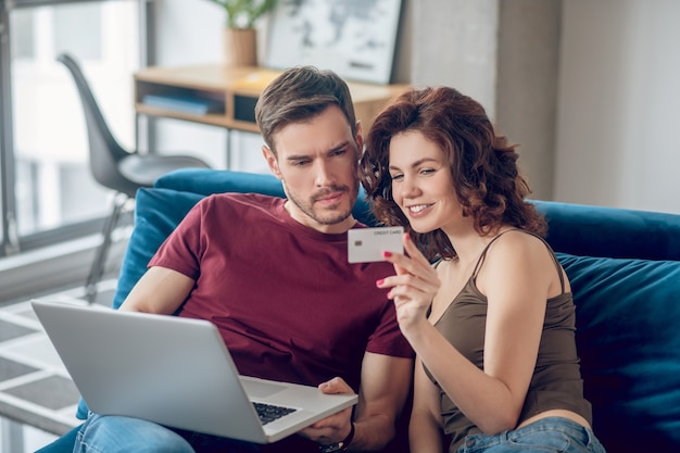 Las compras en línea. Pareja joven eligiendo algo para comprar online