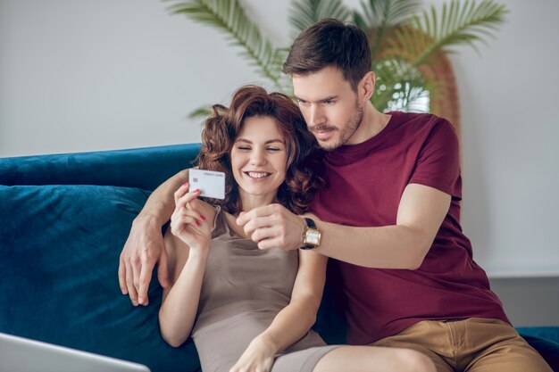 Las compras en línea. Pareja joven sentado en el sofá y eligiendo productos en línea