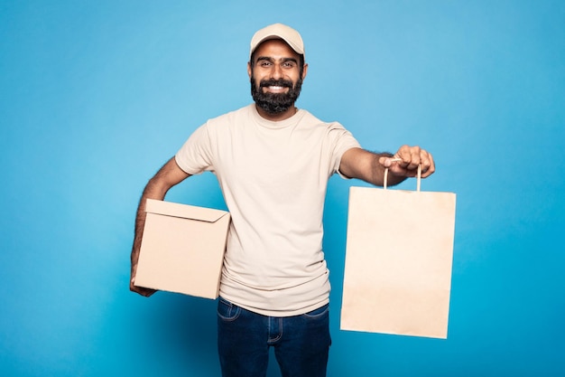 Compras en línea y servicio de entrega mensajero indio positivo dando bolsa de compras y sonriendo a