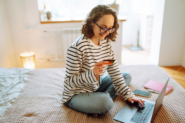 Compras en línea t Inicio Una mujer joven tiene una tarjeta de crédito y usa una computadora portátil Venta de Black Friday