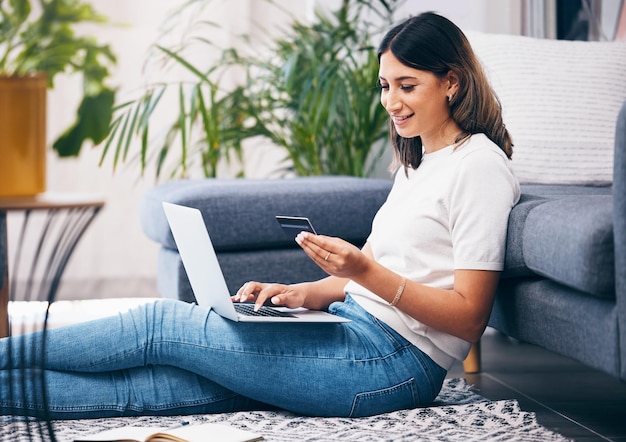 Compras en línea con tarjeta de crédito y mujer en la banca portátil y fintech para un pago fácil en la alfombra del hogar Persona joven o estudiante con computadora para la financiación de la venta de comercio electrónico y la riqueza en su sala de estar