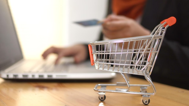 Compras en línea en la tienda de Internet concepto mujer haciendo compras en el portátil con tarjeta de crédito