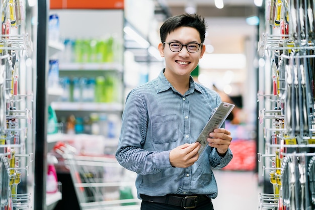 Compras masculinas de clientes asiáticos escolhem produtos da prateleira no fundo do shopping