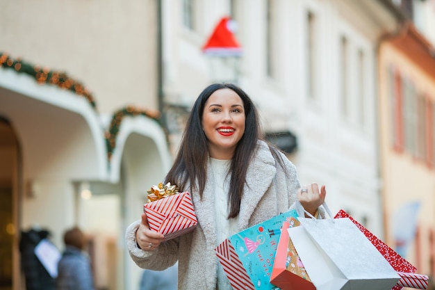 Compras navideñas Joven hermosa morena compra regalos para las vacaciones de Año Nuevo Vacaciones de invierno