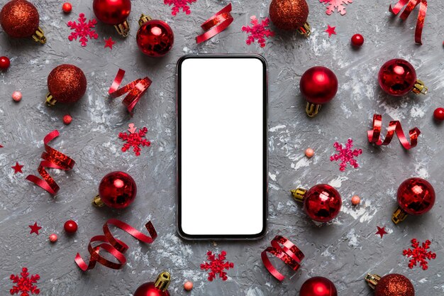 compras navideñas en línea desde el teléfono de casa con pantalla blanca en blanco vista superior móvil inteligente con espacio de copia en fondo de color con decoraciones navideñas bolas vacaciones de invierno ventas de fondo