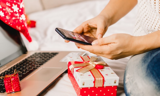 Compras navideñas online. Compradora femenina hace un pedido en el teléfono móvil.