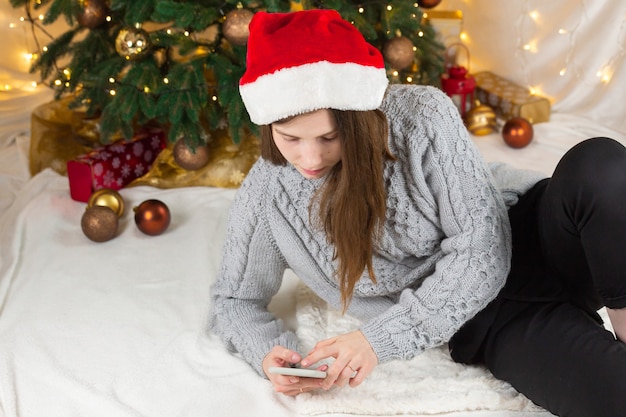 Compras navideñas online. Linda hermosa mujer atractiva navegando a través de su teléfono