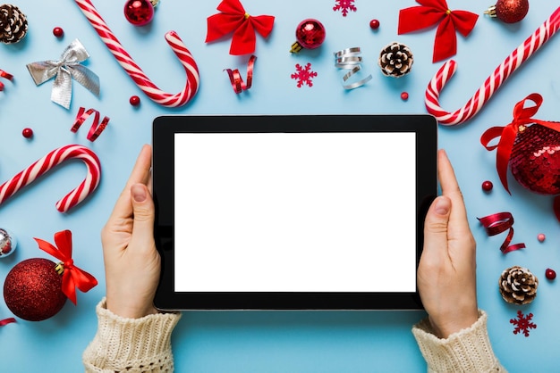 Compras on-line de natal em casa mãos femininas segurando tablet pc com tela branca em branco vista superior mão de mulher segurando tablet com tela em branco Árvore de Natal e presentes no fundo