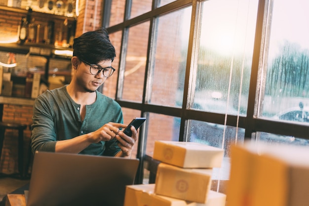 Compras on-line jovens começam pequenos negócios em uma caixa de papelão no trabalho.