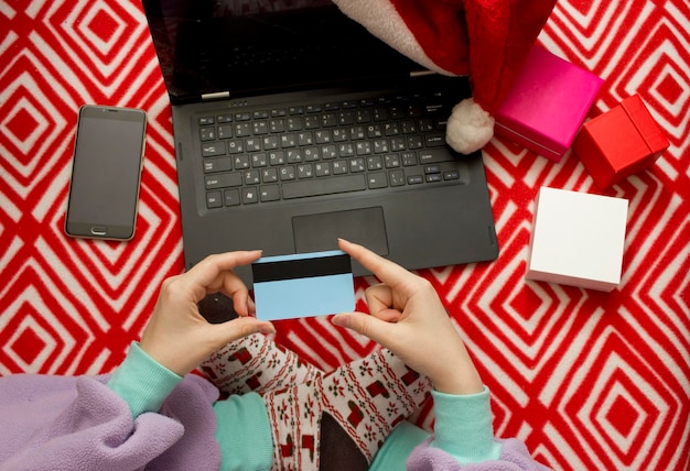 Compras online de Natal. garota de pijama e meias com uma impressão de Natal faz pedidos de presentes na Internet usando um laptop. garota faz pedidos de presentes na Internet usando um laptop.