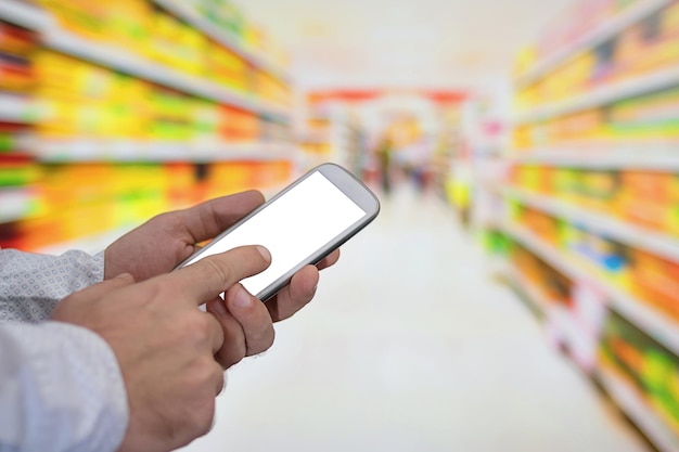 Compras con pantalla táctil en el teléfono móvil. Pedidos por Internet comprando pago de telecomunicaciones. Hombre revisando la lista de compras en su teléfono inteligente en el supermercado.