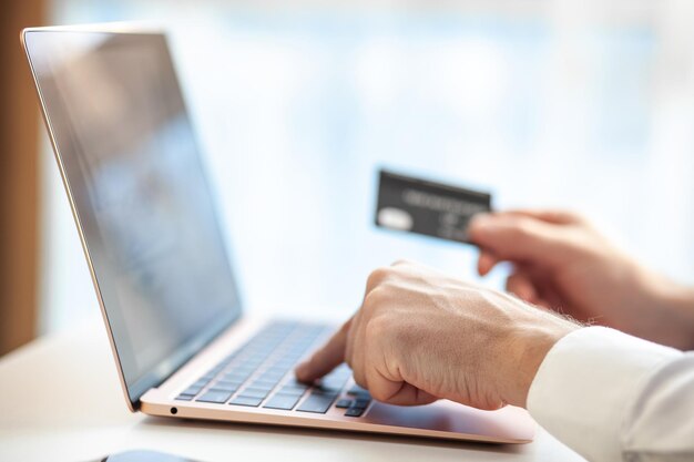 Compras pela Internet e pagamento de serviços compram cartão de crédito. As mãos digitam texto e inserem dados