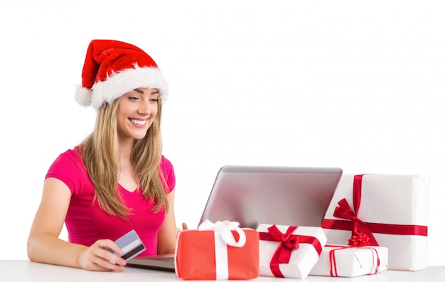 Compras rubias festivas en línea con la computadora portátil
