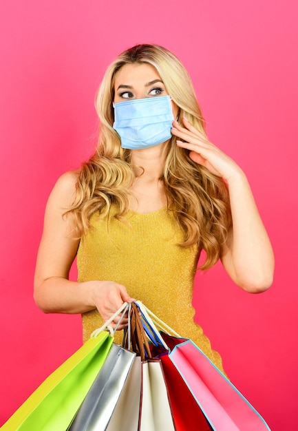 Compras seguras y saludables. mujer en máscara de respiración con bolsas de papel. comprador protegerse del brote pandémico de coronavirus. comprando mascarilla médica. Concepto de déficit epidémico. cuarentena de virus.