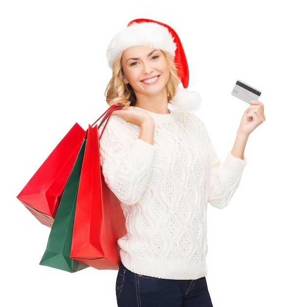 compras, venda, presentes, natal, conceito de Natal - mulher sorridente com chapéu de ajudante de Papai Noel com sacolas de compras e cartão de crédito