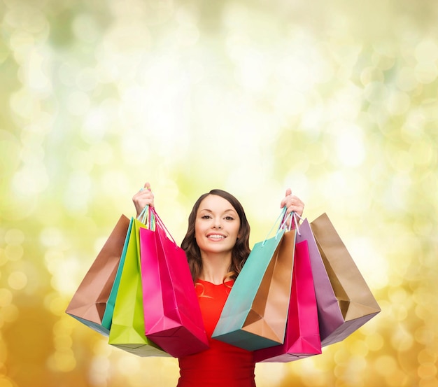 compras, venda, presentes, natal, conceito de Natal - mulher sorridente com vestido vermelho com sacolas de compras coloridas