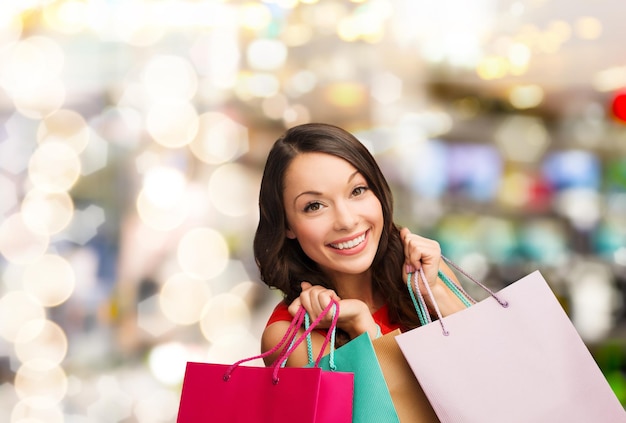 compras, venda, presentes, natal, conceito de Natal - mulher sorridente com vestido vermelho com sacolas de compras