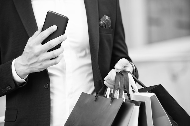 Compras en venta de lunes cibernético o viernes negro Nueva tecnología para comunicación empresarial Bolsas de compras y teléfono inteligente en manos del hombre Después de un día de compras marketing digital para una compra exitosa en línea