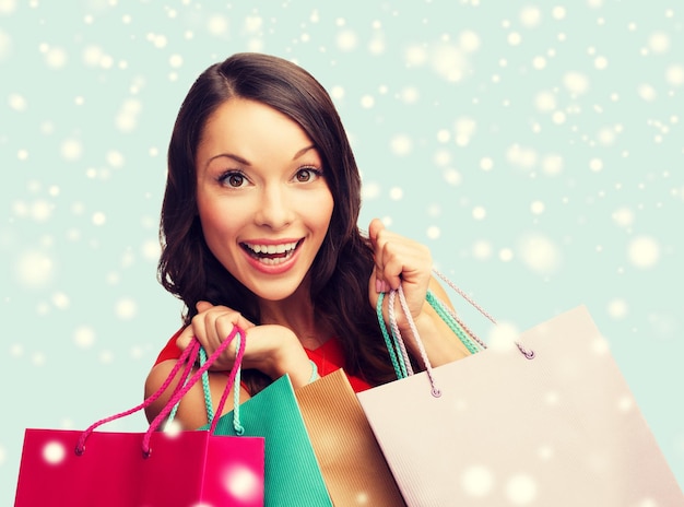 compras, venta, regalos, navidad, concepto de navidad - mujer sonriente, en, vestido rojo, con, bolsas de compras