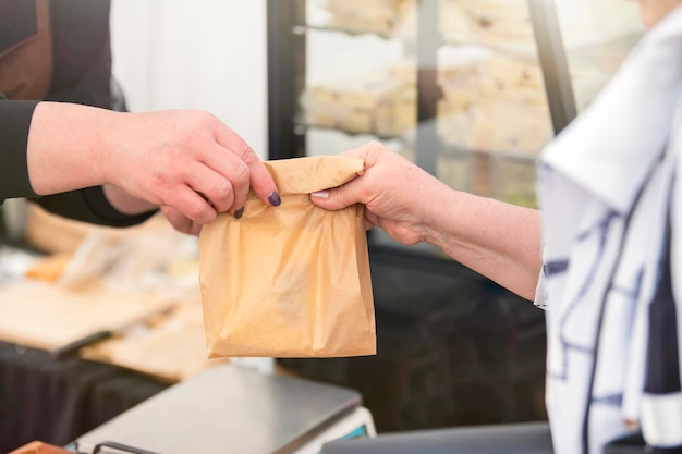 Compre doces em uma confeitaria a mulher pega um saco de biscoitos doces do vendedor e paga