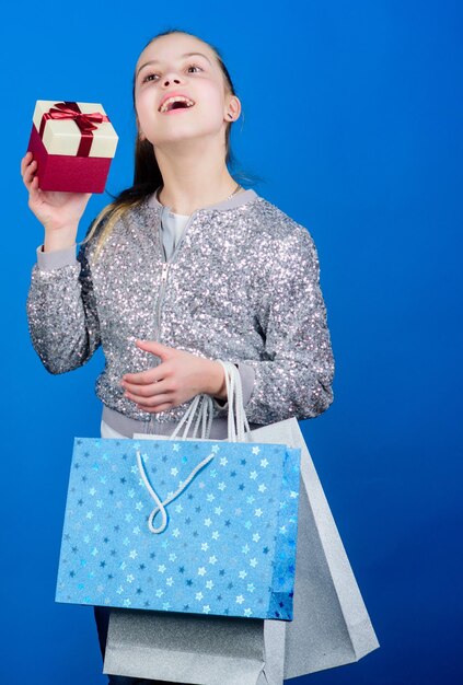 Compre o que você quer Garota com sacolas de compras fundo azul Compras e compras Sexta-feira negra Desconto de venda Dia de compras Pacotes de espera para crianças Moda infantil Caixa de presente surpresa