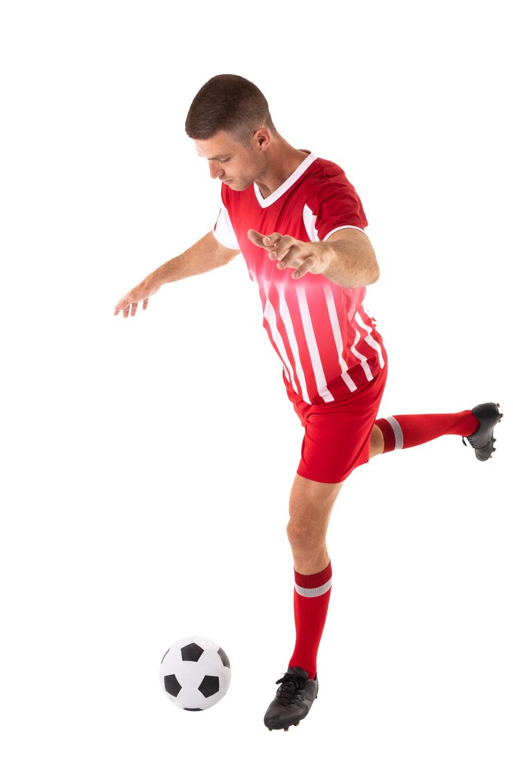 Foto comprimento completo de jovem atleta caucasiano chutando uma bola de futebol contra um fundo branco
