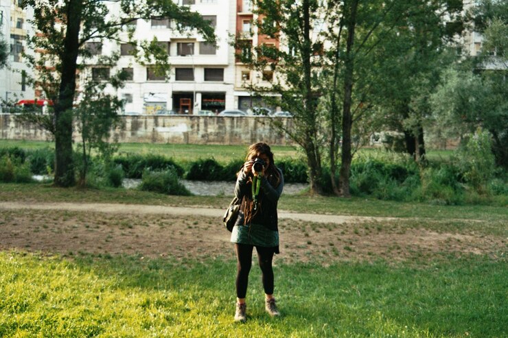Foto comprimento completo de menina adolescente fotografando enquanto está de pé no prado