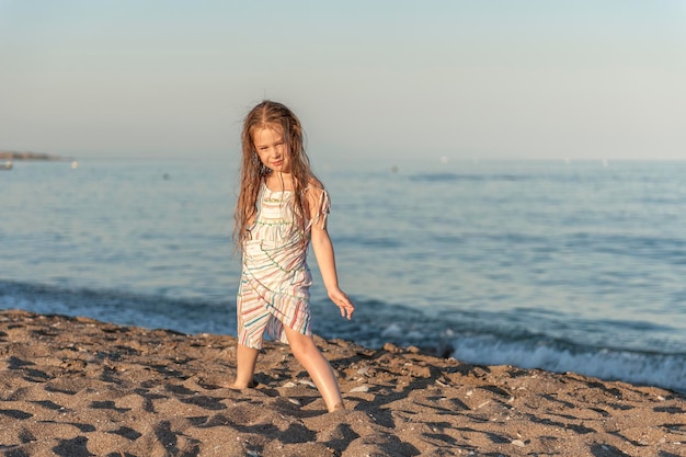 Comprimento completo de menina de pé na costa na praia