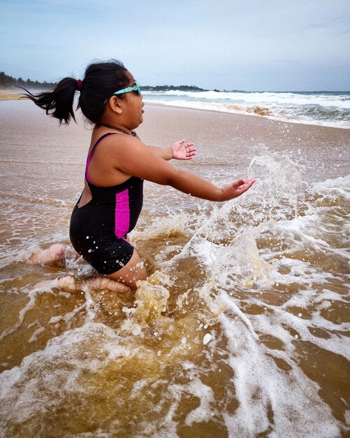 Foto comprimento completo de menina salpicando água no mar