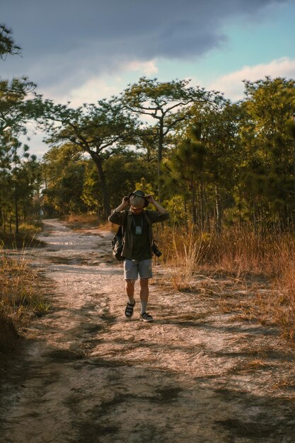 Foto comprimento completo de mulher caminhando na rua em meio a árvores contra o céu