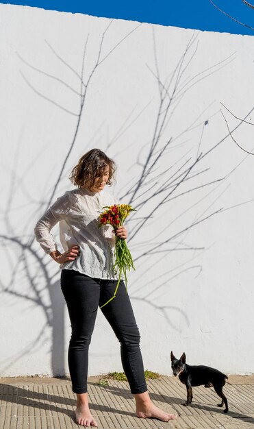 Foto comprimento completo de mulher com cão contra plantas