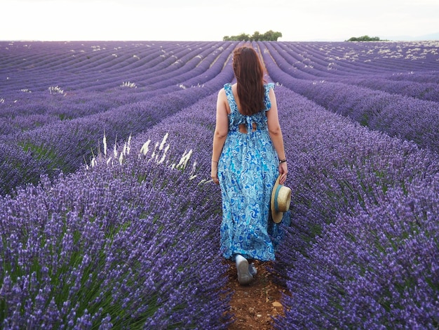 Comprimento completo de mulher de pé por flores roxas no campo
