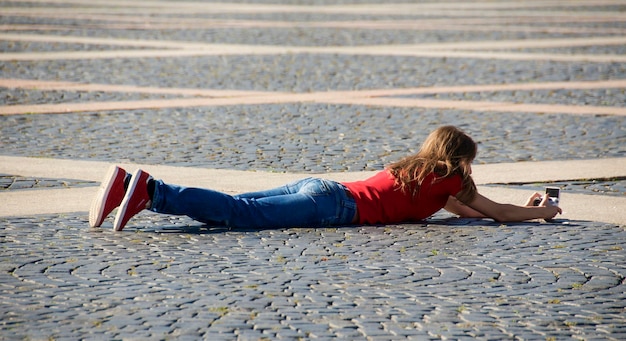 Foto comprimento completo de mulher fotografando enquanto está deitada na rua