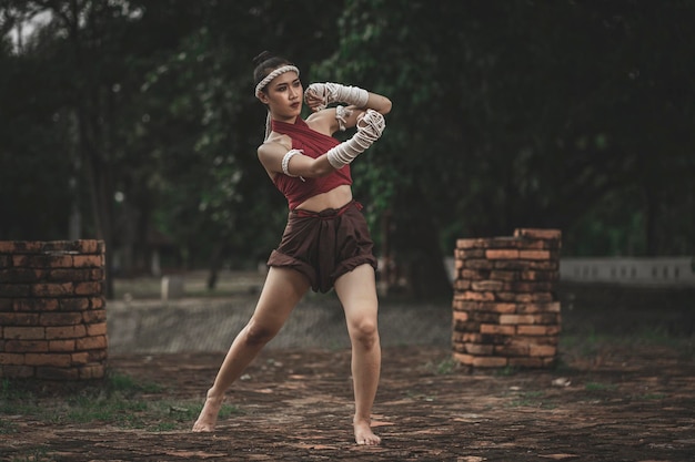 Comprimento completo de mulher praticando kickboxing enquanto está de pé contra árvores