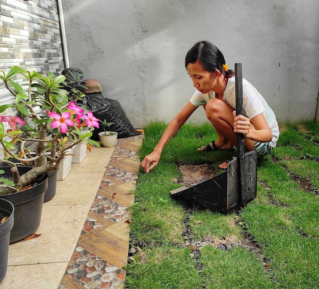 Foto comprimento completo de mulher segurando uma flor enquanto está de pé na planta