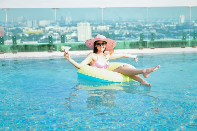 Foto comprimento completo de mulher sorridente com bebida na piscina
